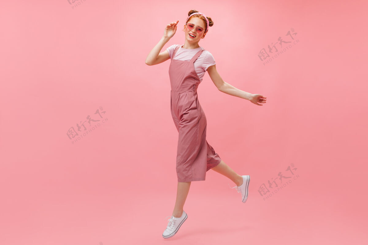 女士穿着粉色连身衣 t恤和时髦眼镜的活跃女性在粉色背景上移动优雅眼睛红发