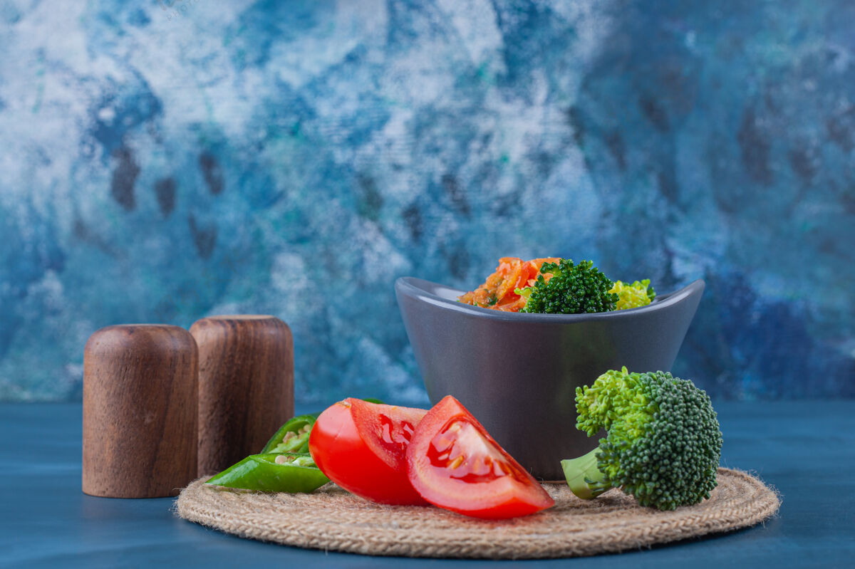 蛋白质碗里的鸡汤和蓝色表面的三脚架上的蔬菜片禽类蔬菜胡椒