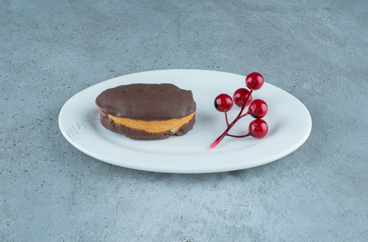 美味巧克力蛋糕和一簇圣诞浆果放在大理石背景的盘子上高质量的照片蛋糕美味巧克力