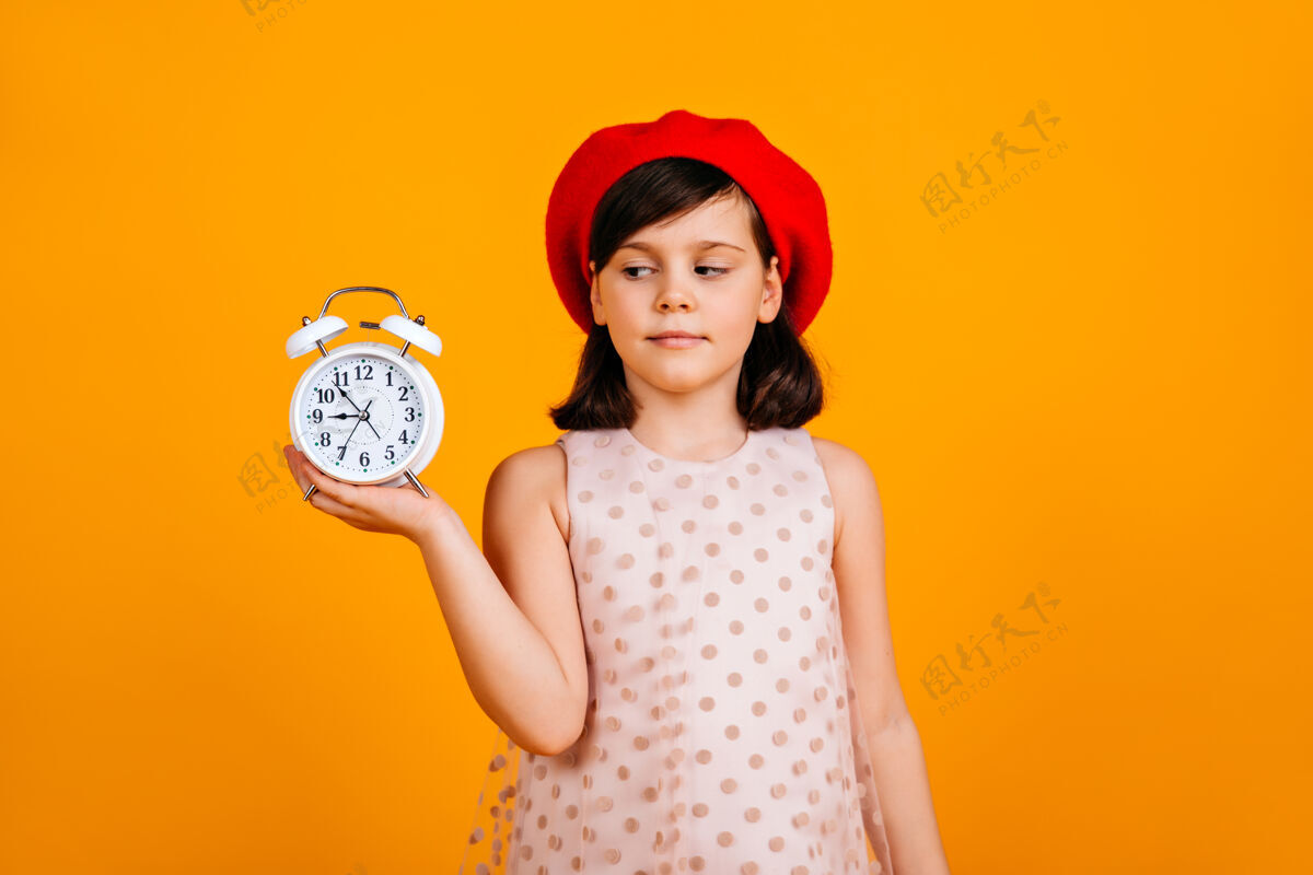 欢呼穿着时尚贝雷帽的法国小孩高加索小孩拿着钟在黄色墙上摆姿势明亮情绪贝雷帽