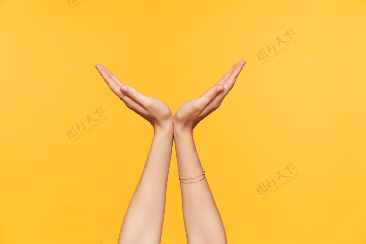折叠年轻的皮肤白皙的女人举起她的手掌折叠成半圆形 同时站在黄色背景上身体语言和符号的概念符号手指手臂