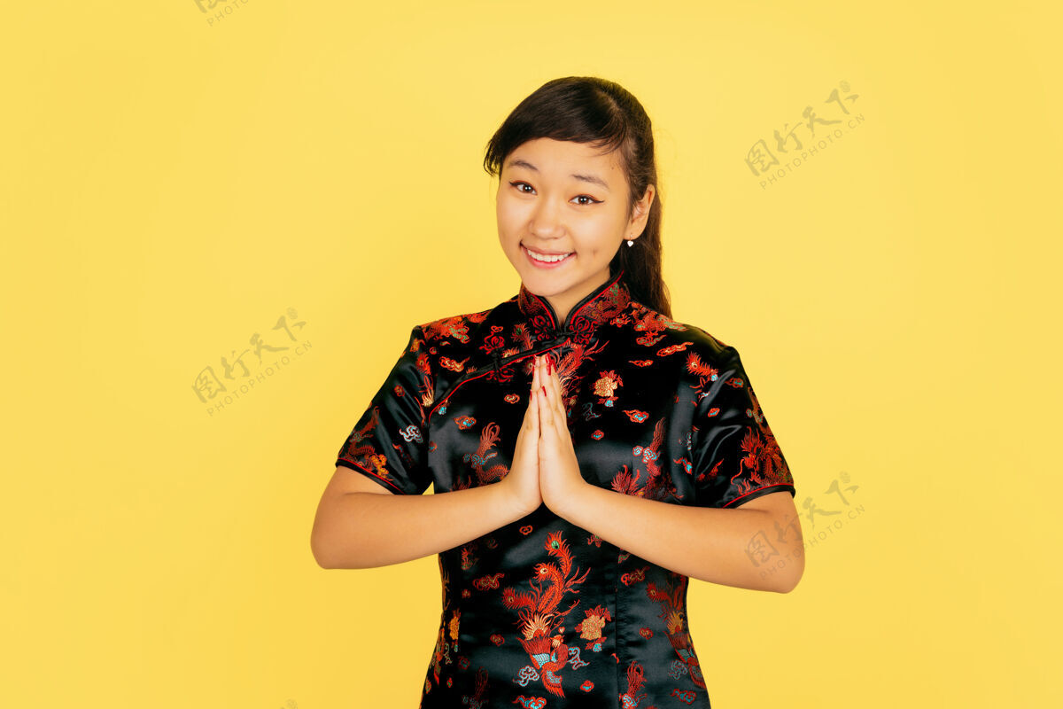 传统微笑 谢谢可爱中国新年快乐黄色背景上的亚洲女孩肖像穿着传统服装的女模特看起来很快乐庆祝 人类情感复制空间年轻普通话欢呼