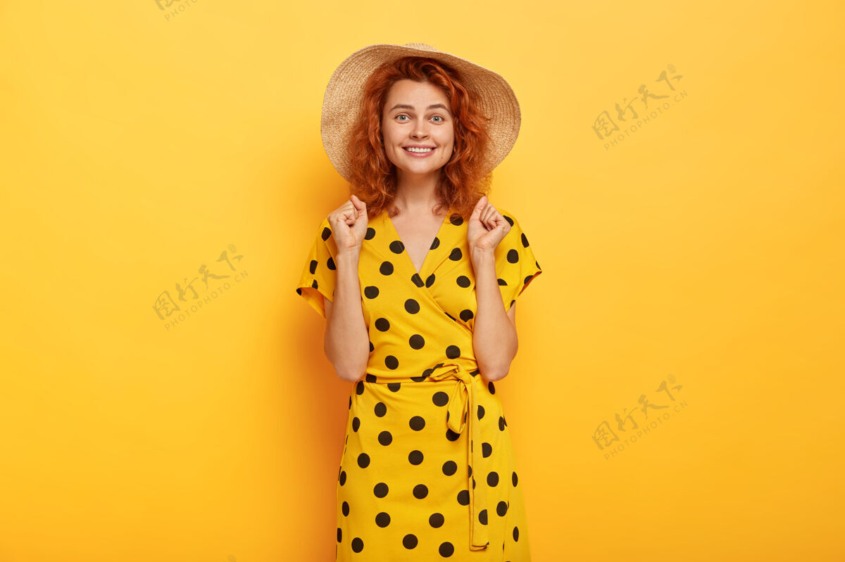 年轻身着黄色波尔卡裙 头戴草帽的快乐红发女人女人时尚欢呼