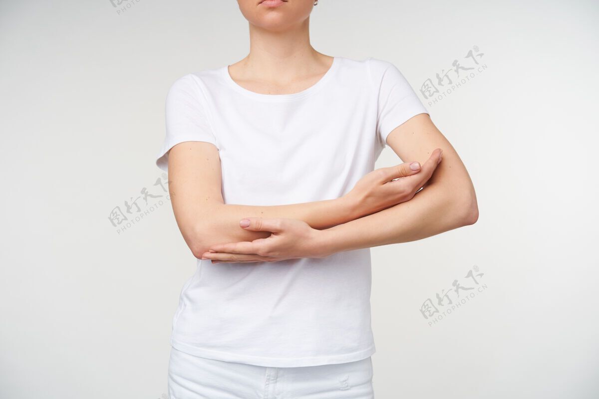 手室内拍摄的年轻女性合拢双手放在胸前 同时模仿摇摇欲坠的孩子 穿着白色基本款t恤站在白色背景上年轻休闲手势