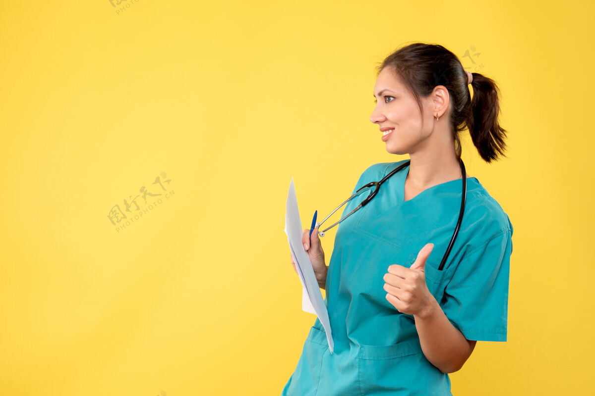 专业正面图年轻的女医生穿着医疗衬衫 黄色的桌子上放着文件视图护士人