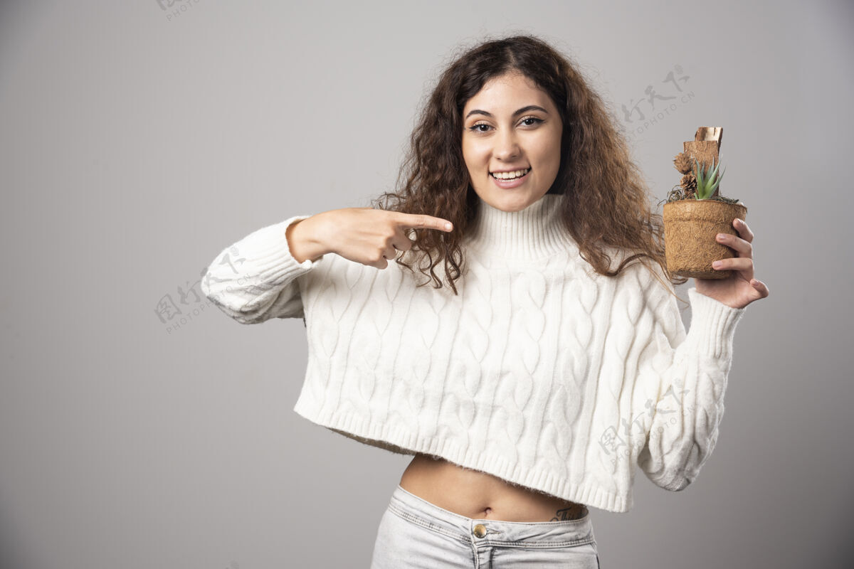 女士年轻女子拿着一株植物 指着它高质量的照片植物学花盆人