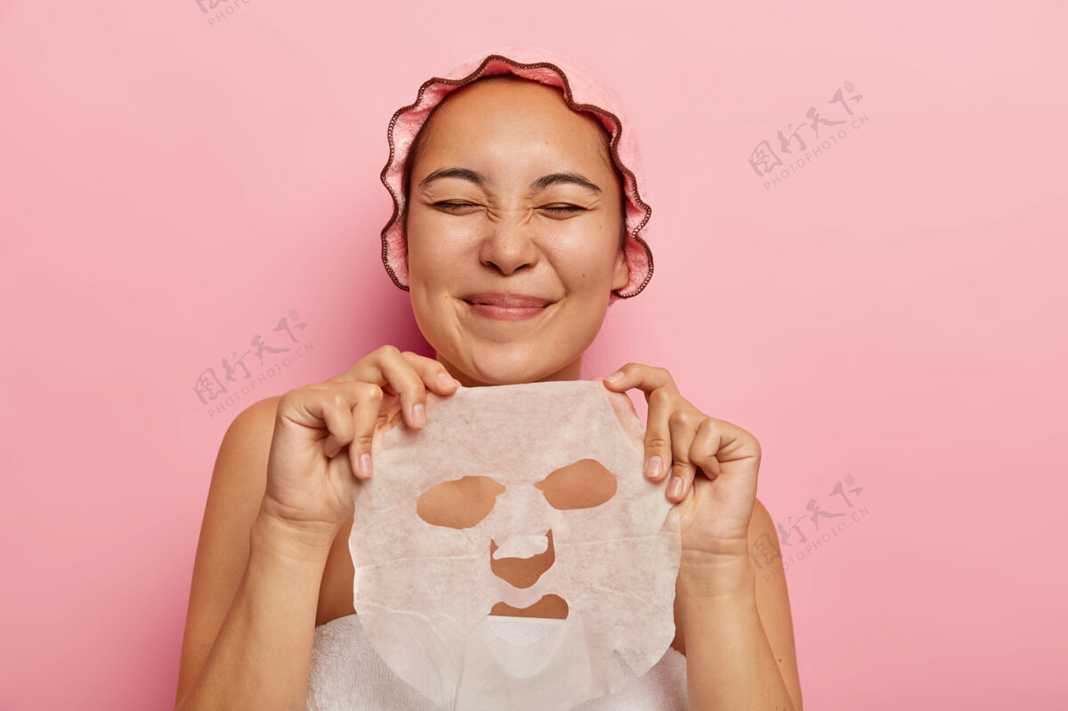 玫瑰高兴的亚洲女性拿着面膜 准备敷在脸上 从美容中得到乐趣 闭上眼睛关闭满意享受