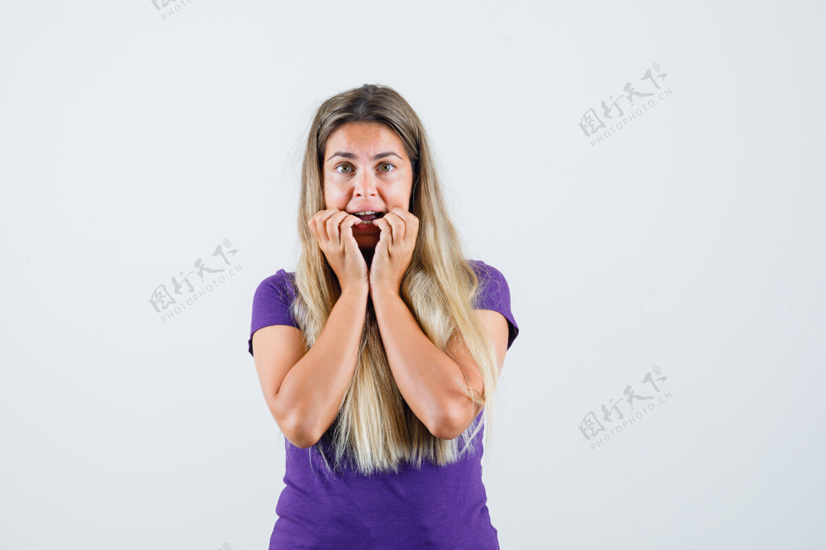 害怕穿着紫罗兰色t恤咬指甲的年轻女士 看起来很害怕 正面视图紫罗兰看咬