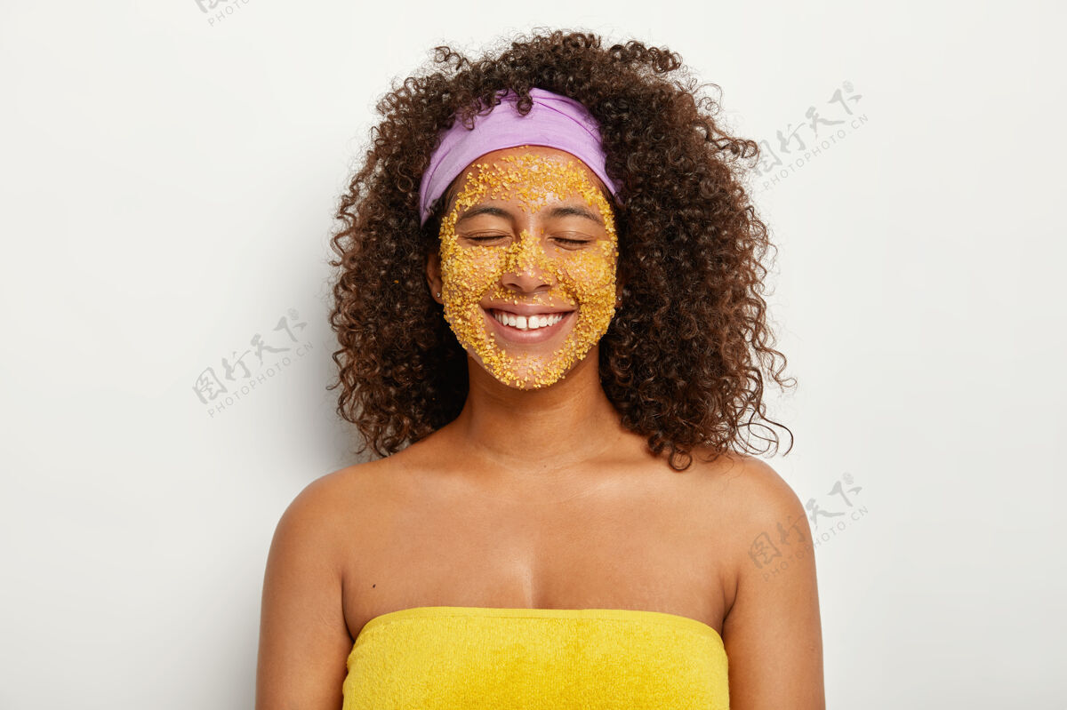头带快乐快乐的非洲发型女人做天然黄海盐面部磨砂膏 让皮肤更光滑 消除刺激和黑斑 改善矿物质平衡 有美容常规 用毛巾包着满意站立愉悦
