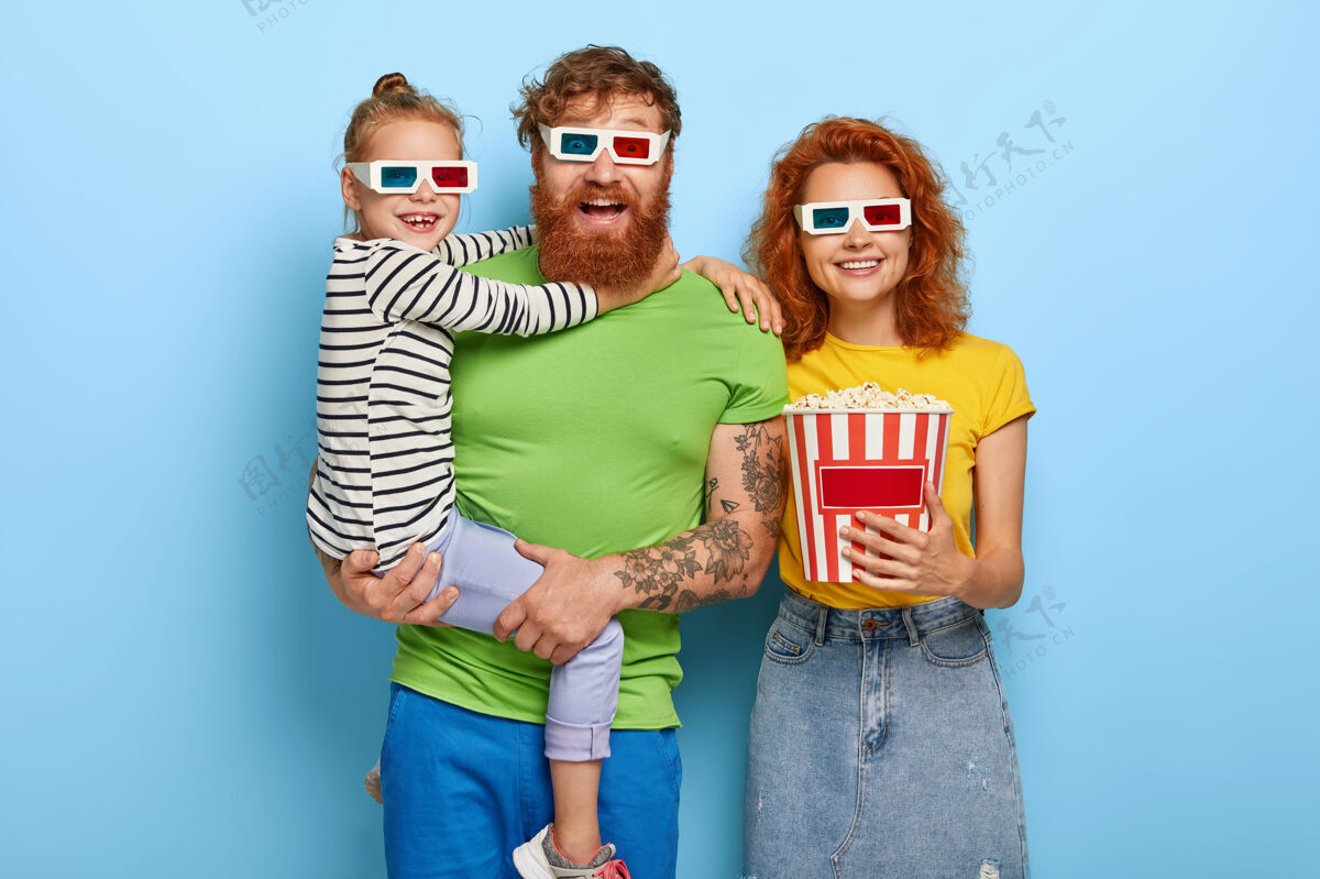 快乐快乐的一家人在电影院欣赏电影或卡通 戴上3d眼镜 被清凉的声音和视觉效果逗乐 吃着美味的零食小女孩在爸爸的手上 拥抱着他人 休闲 周末男朋友吃姜
