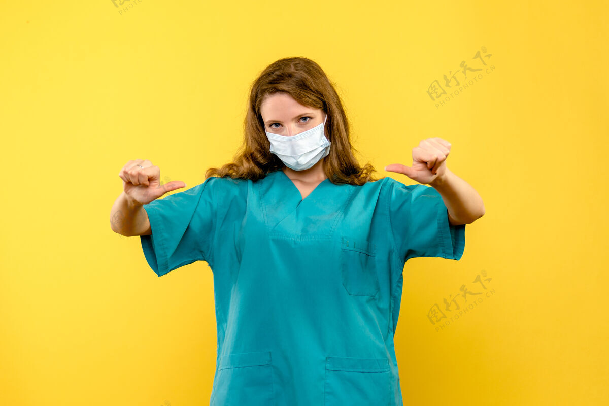 健康前视图年轻女医生戴着面具在淡黄色的空间里人服装视图