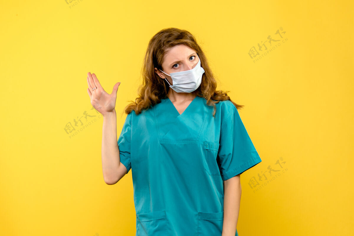 视图黄色空间里戴着面具的女医生的正视图医学黄色肖像