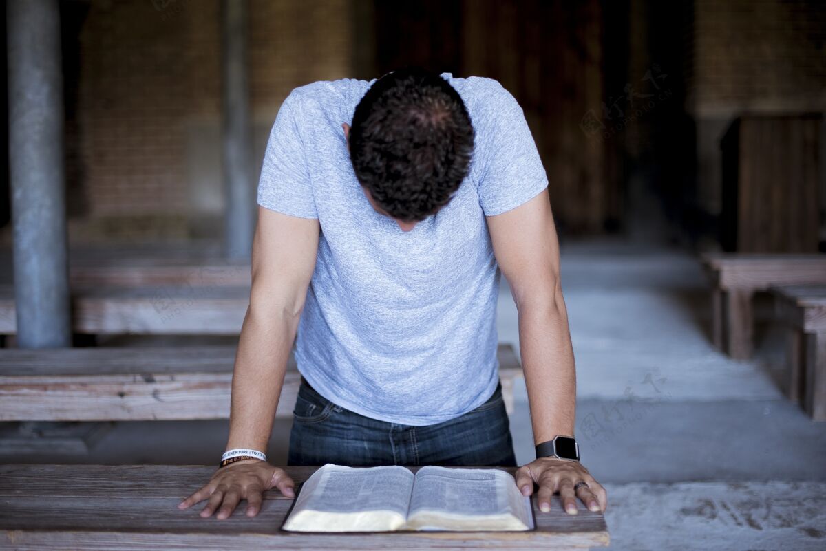 年轻人一个男人在木桌上读圣经的特写镜头宗教基督徒圣经