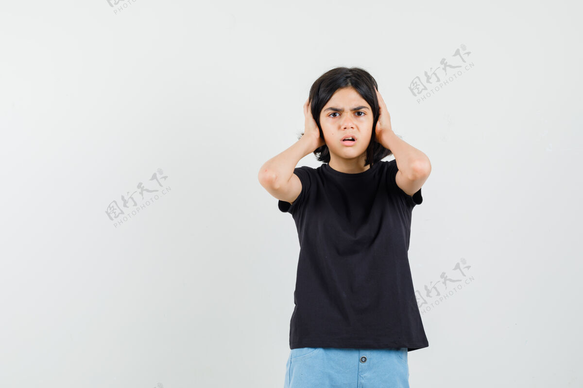 持有小女孩穿着黑色t恤 短裤 手放在耳朵上 看起来很害怕 正面视图青少年年轻和平