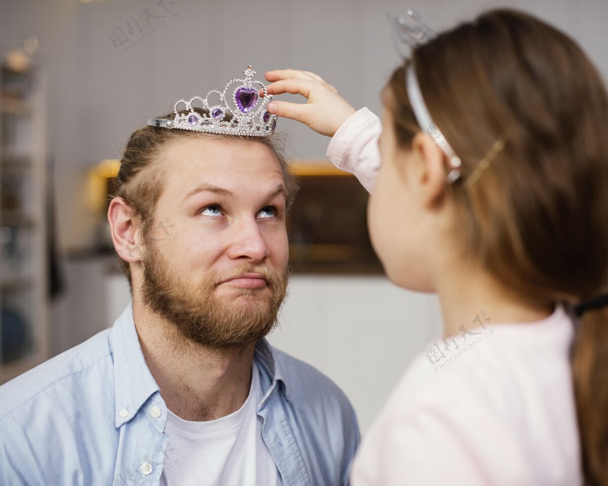 水平小女孩把王冠戴在父亲头上的侧视图世界各地父亲爸爸