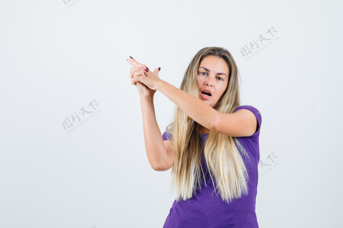金发身着紫罗兰色t恤的金发女子 展示持枪姿势 看起来很自信 正面视图枪手年轻