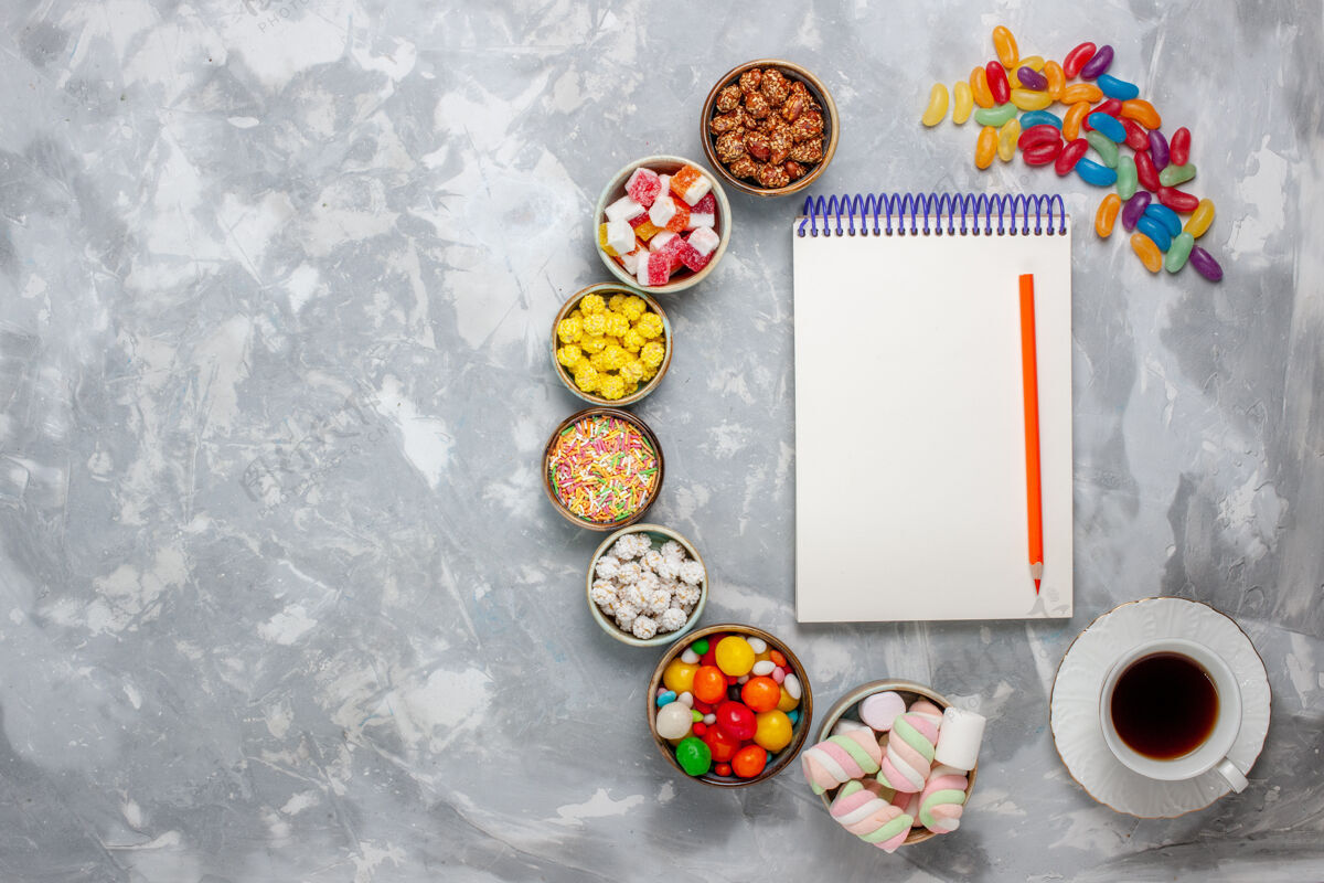 庆祝顶视图糖果组成不同颜色的糖果与棉花糖记事本和茶上的白色办公桌糖糖果邦邦甜封视图食物桌子