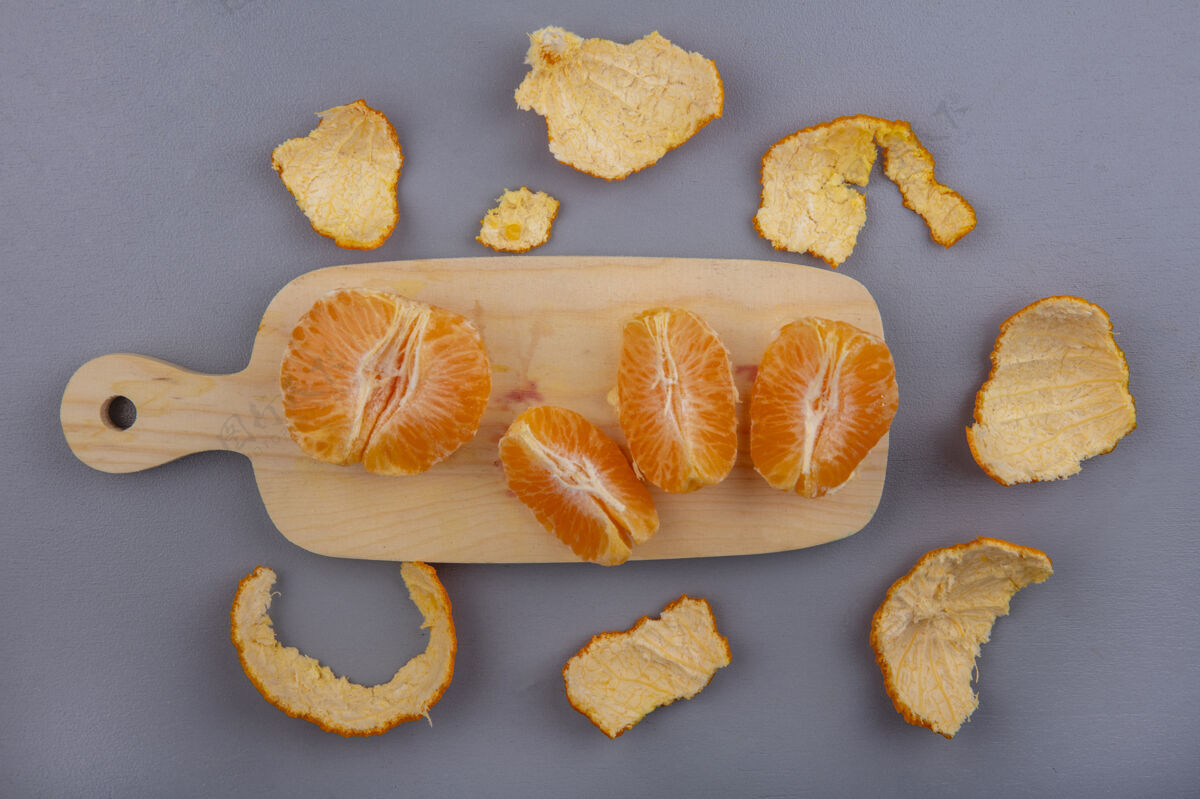 灰色俯视图剥皮的橘子与灰色背景上的果皮砧板视野水果柑橘