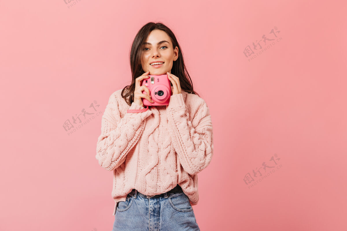 套头衫微笑的黑发女士穿着时尚的毛衣 在孤立的背景下摆出粉红色的相机衣服微笑深色