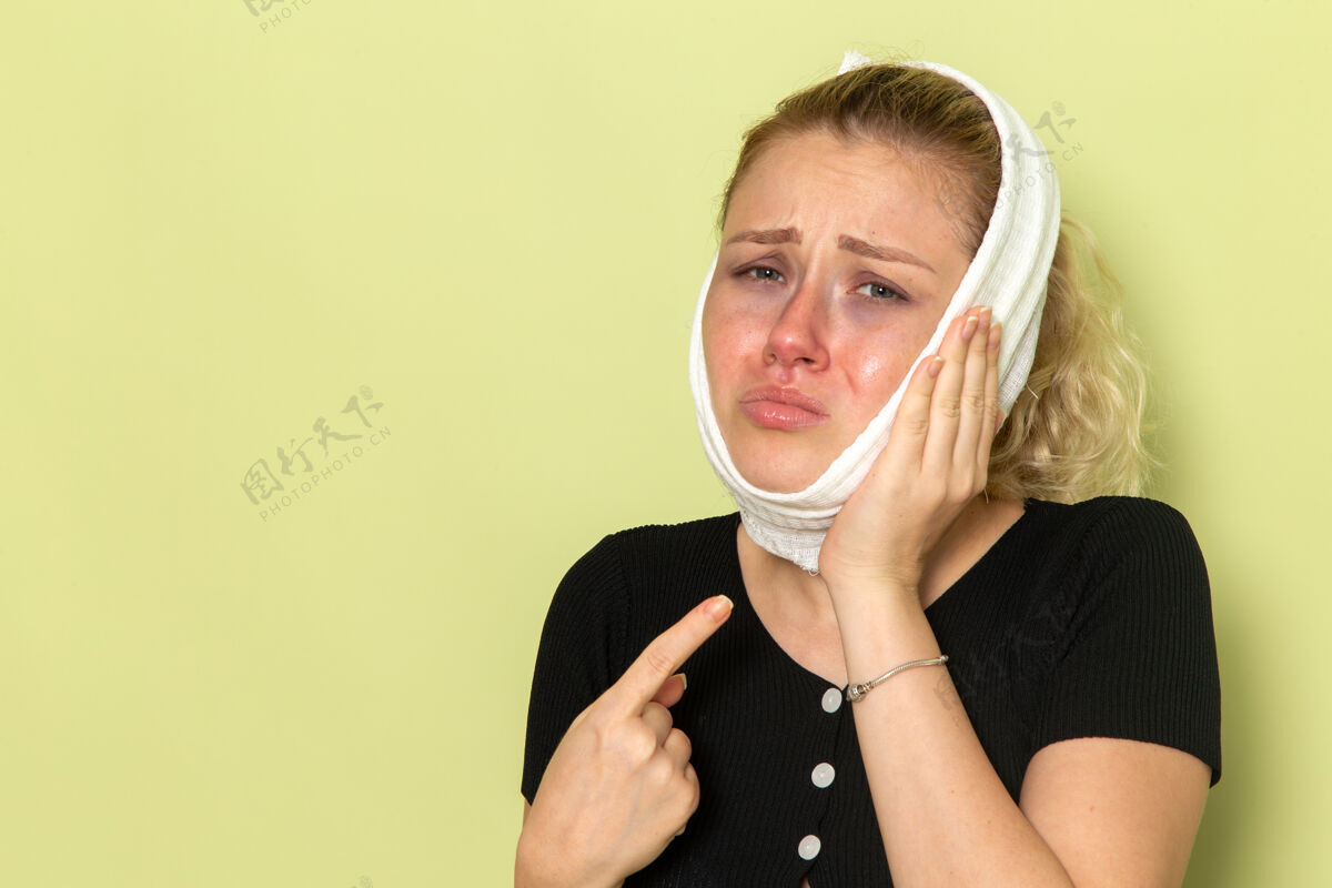 生病正面图年轻女性 头上围着白毛巾 感觉很不舒服 绿色墙壁上牙疼生病生病的女健康女孩年轻牙痛毛巾