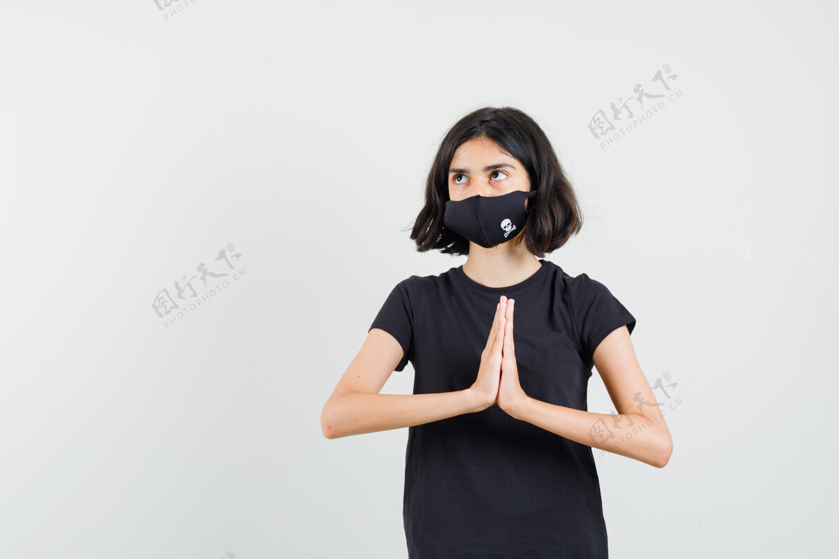 和平穿着黑色t恤的小女孩 戴着面具 展示着纳马斯特的姿势 正视图显示青年人