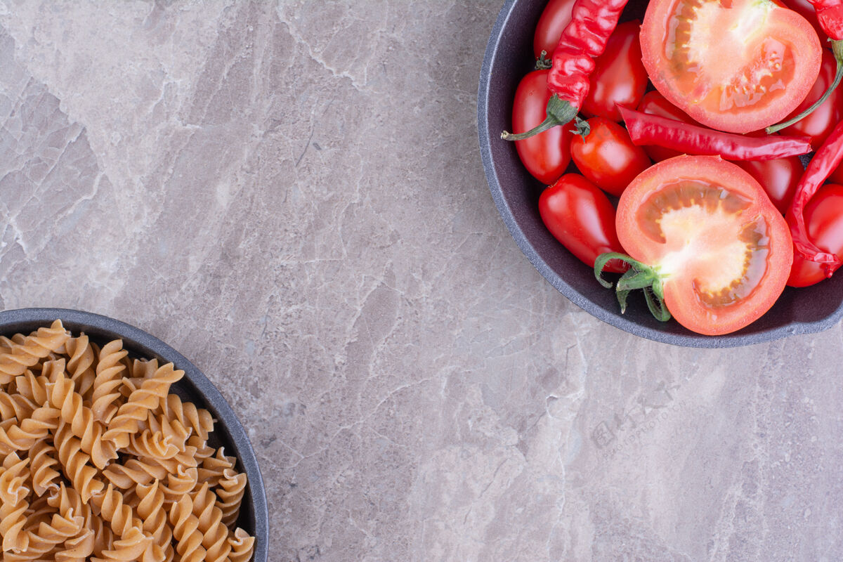 自制红色的生意大利面和樱桃番茄放在大理石表面健康菜单极简
