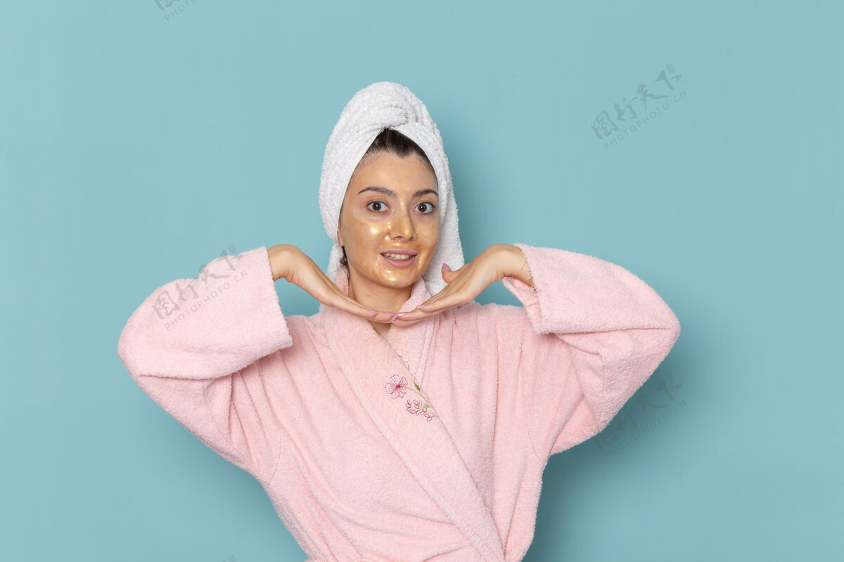 浴袍正面图身着粉色浴袍的年轻女性淋浴后在蓝色墙壁上摆姿势美净水自理淋浴人自理淋浴