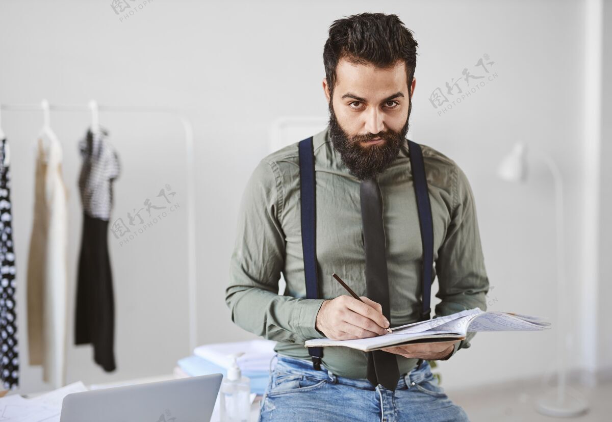 裁缝帅气的男时装设计师在工作室与文件的正面视图个人套装时装师