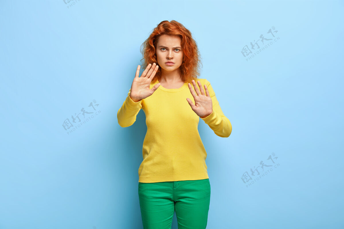 严重严重不满的女人有一头红色的卷发 摆出停止的姿势 在镜头前伸着手掌 拒绝什么女士卷曲拒绝