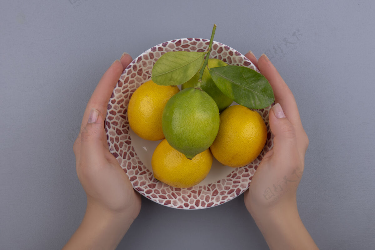食物顶视图女人拿着柠檬和石灰在灰色背景板酸橙新鲜视野