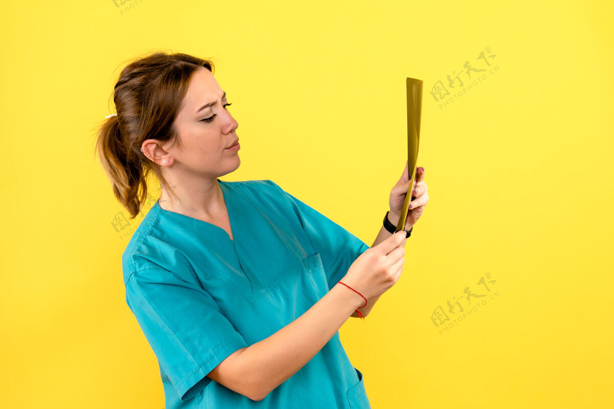 医生黄色墙上女兽医拿着x光片的正面图X光听诊器工作