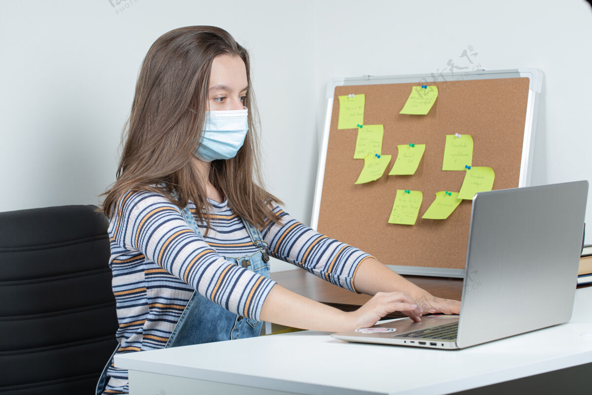 居家戴口罩在办公室工作的年轻女员工 正在采取预防措施消毒制服药物