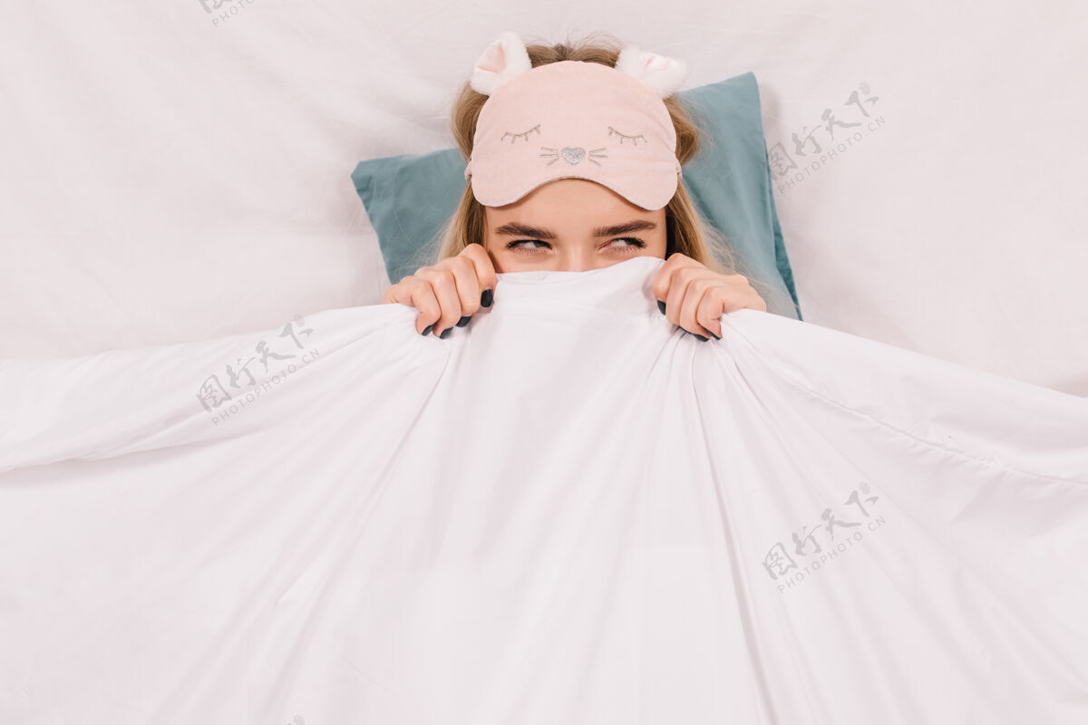 模型戴着睡眠面具的可爱女人在床上摆姿势美女睡眠枕头