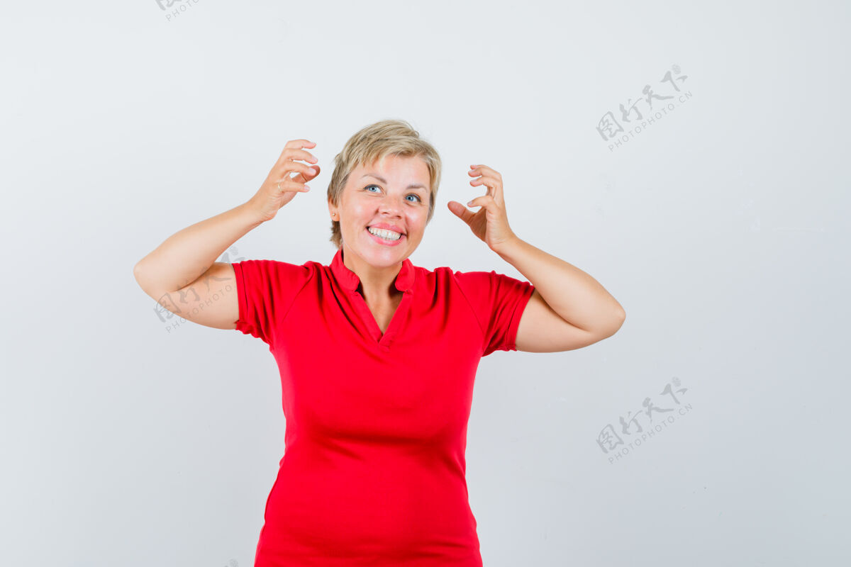 姿势穿红色t恤的成熟女人假装摘下耳机 看起来很快乐脸看人