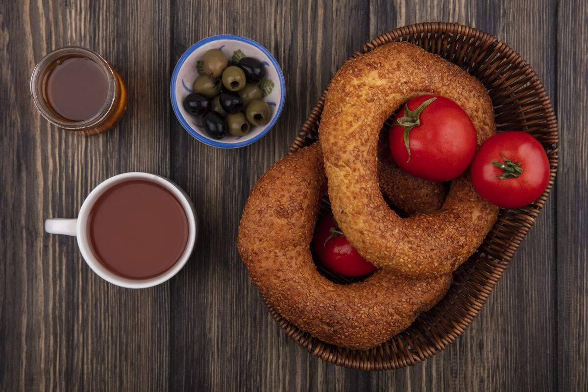 碗土耳其百吉饼的顶视图 桶上放着西红柿和橄榄 碗里放着茶和蜂蜜 背景是木制的土耳其木头餐