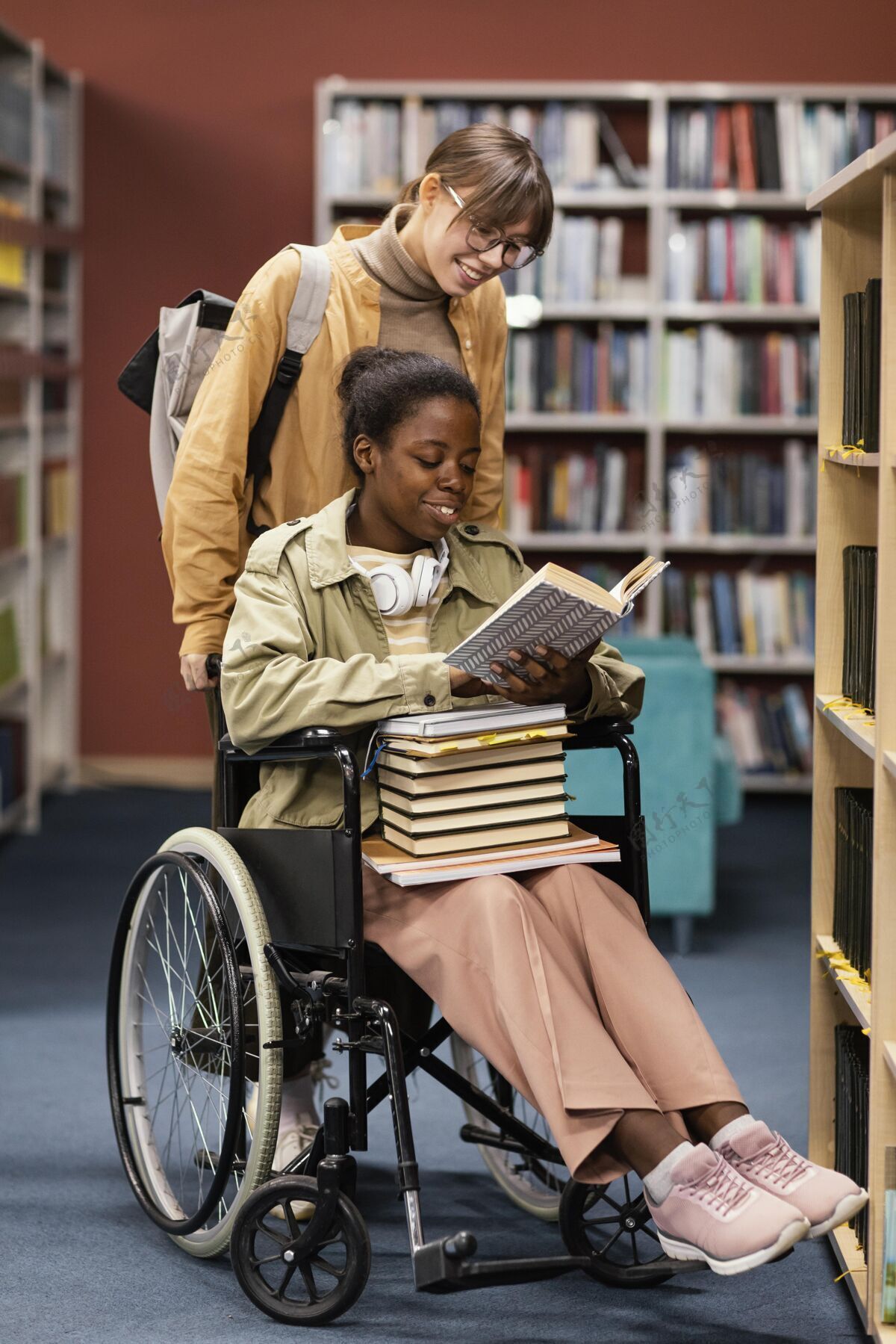 学习帮助轮椅上的同事为一个项目选书的女孩学生教育社区