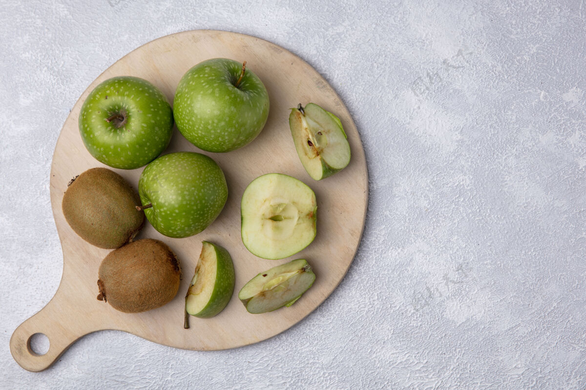 水果俯视图绿色的苹果和猕猴桃在一个白色背景的砧板上切顶部绿色