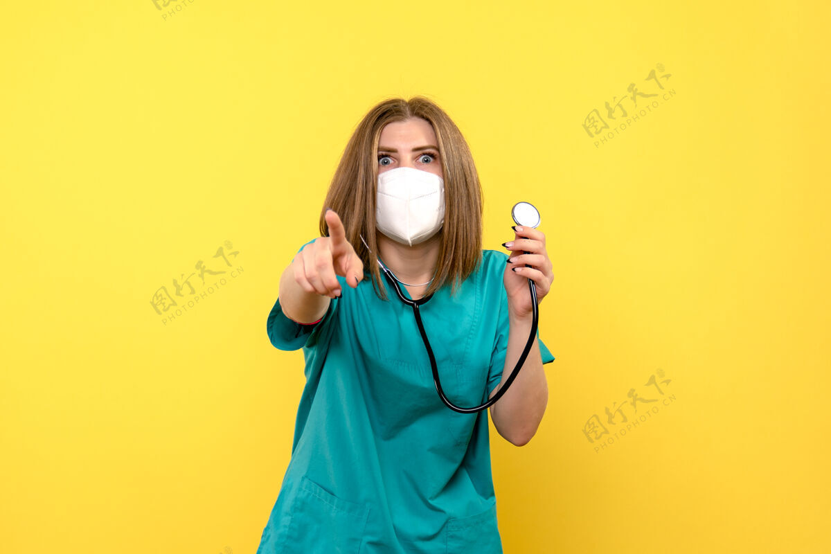 黄色黄色墙上戴着面罩和眼压计的女医生的正视图医院女士面具