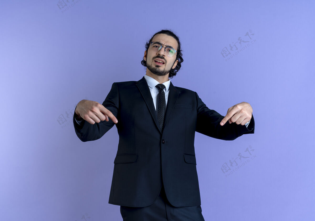 生意一个穿着黑西装戴着眼镜的商人站在蓝色的墙上 手指指着自己 看上去很不高兴公民生意人手指