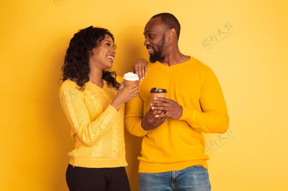 女性年轻感性的非裔美国人 穿着黄色背景的明亮休闲服美丽的情侣人类情感的概念 面部表情 关系 广告一起喝咖啡姿势化妆品夫妇