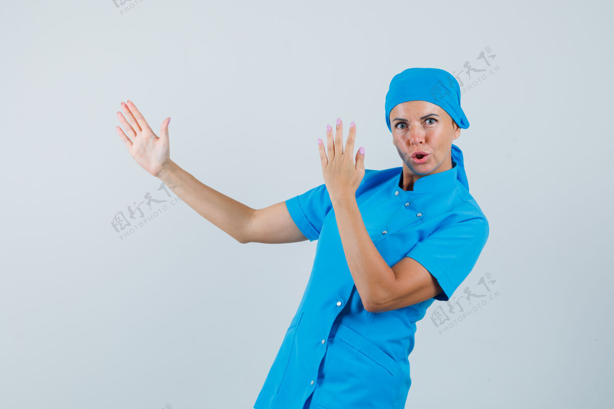病人身穿蓝色制服的女医生展示空手道斩动作 看起来很自信 正面视图女人工作人员制服