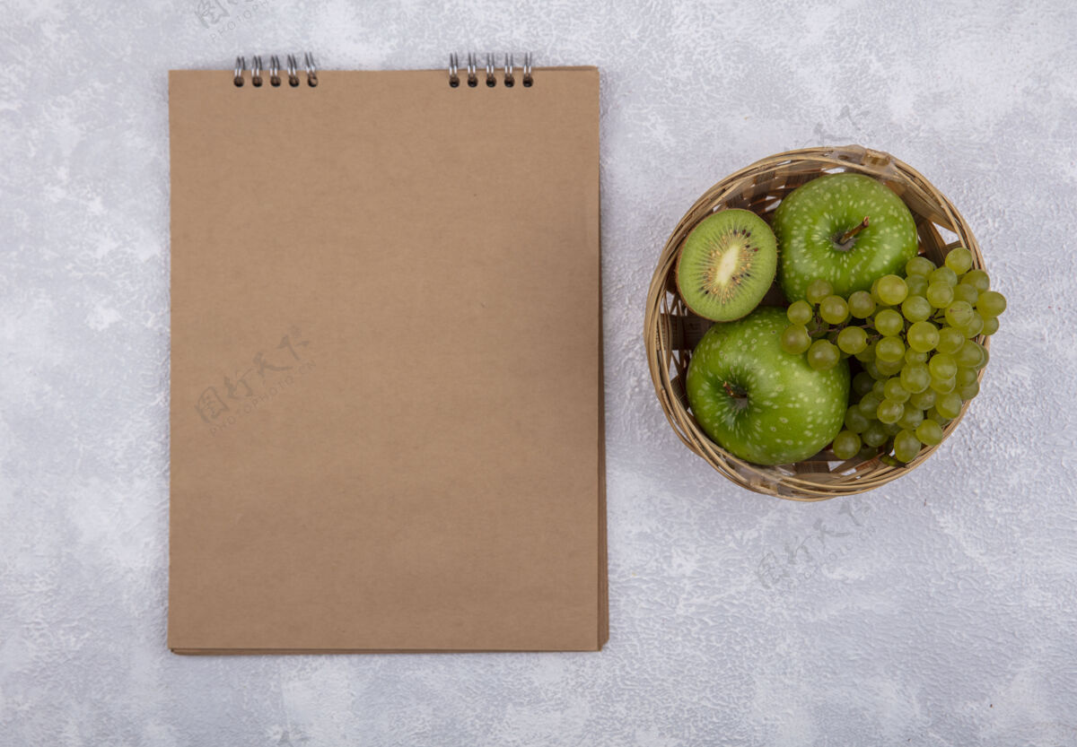 葡萄顶视图复制空间绿色苹果绿色葡萄和猕猴桃楔形篮子棕色记事本白色背景视图新鲜绿色