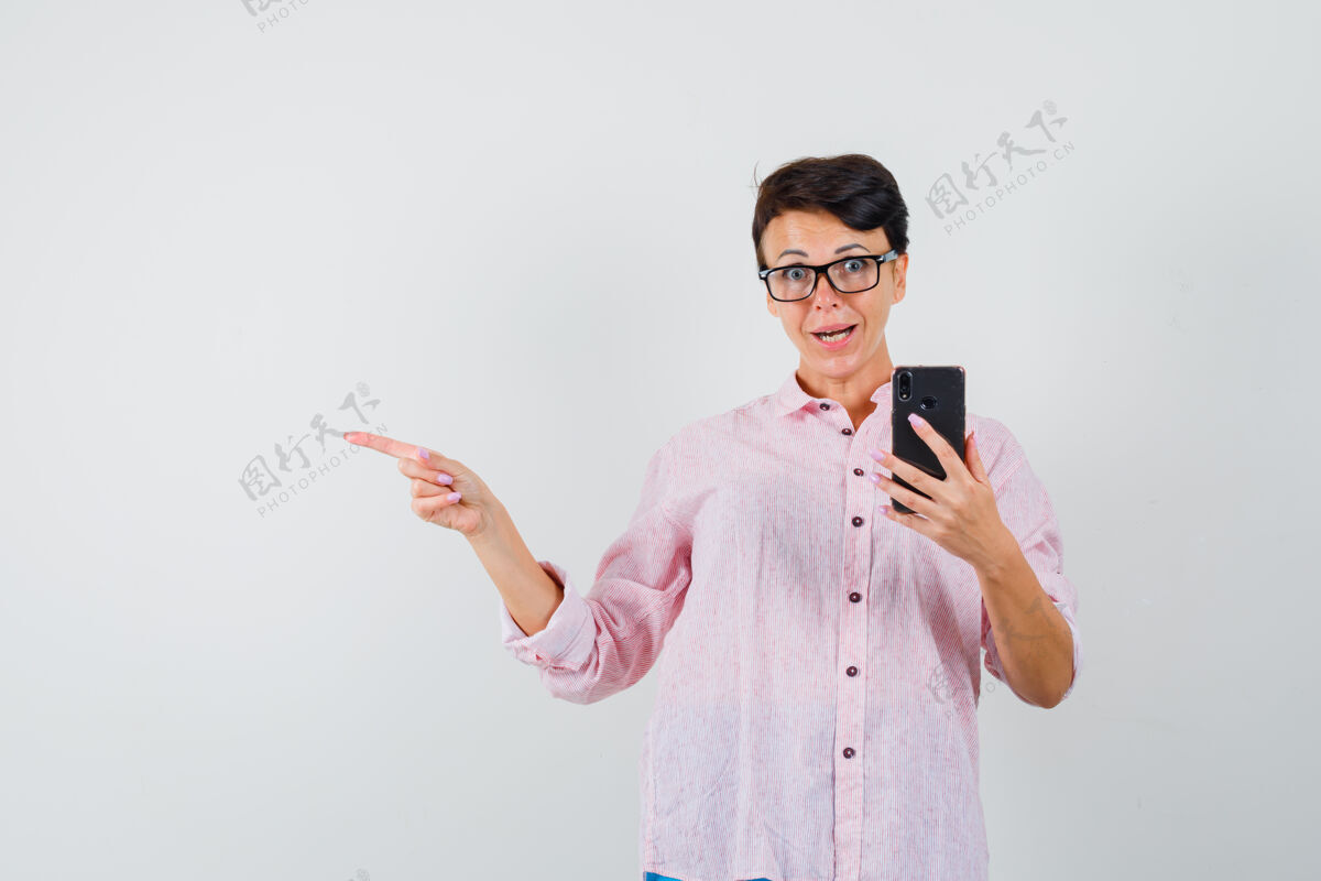 疾病女性指着一边拿着手机在粉红色衬衫和期待兴奋 前视图电话兴奋同时