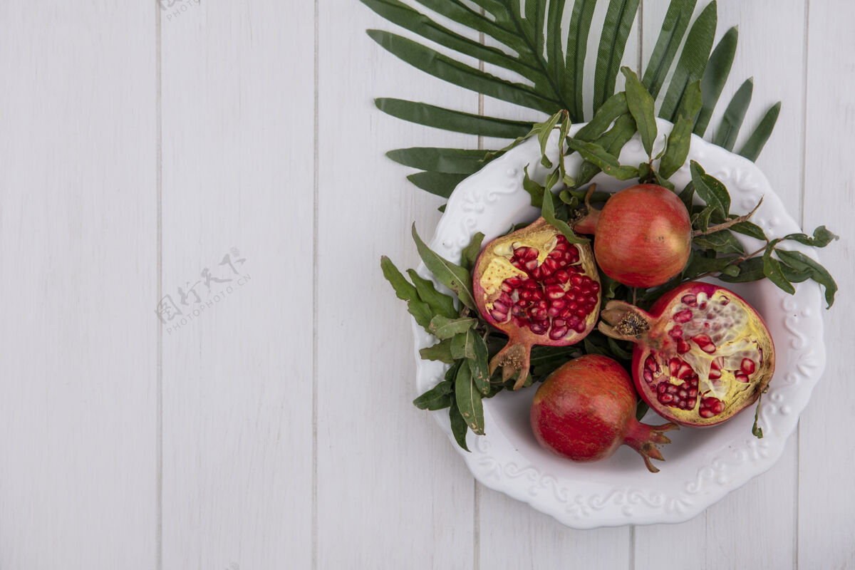 石榴顶视图复制空间石榴与枝叶在一个白色的背景上白色盘子新鲜食物水果