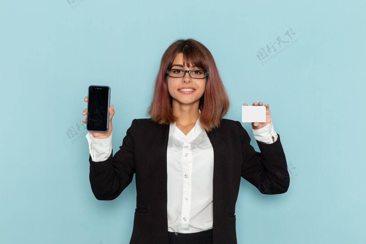办公室正面图身着正装的女上班族手拿着蓝色的名片和手机持有工作电话