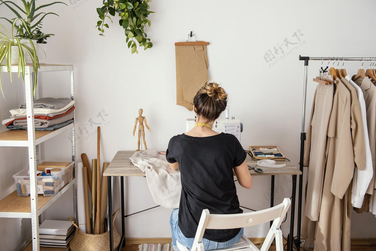 裁缝在工作室工作的女裁缝的后视图缝纫缝纫机卧式