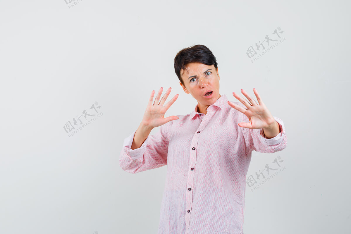 手掌身穿粉色衬衫的女性 展示手掌保护自己 看起来很害怕 正面视图年轻人应用程序呼吸