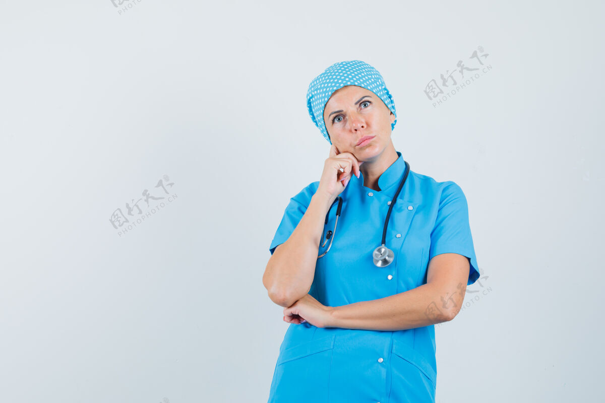 成人女医生穿着蓝色制服抬头 神情沉思前视图女人年轻人服务