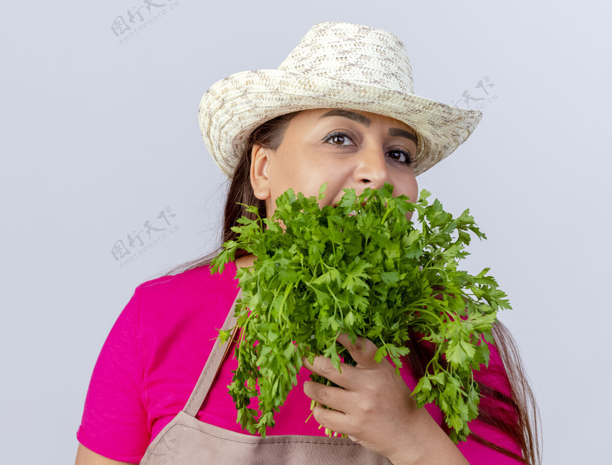新鲜围裙戴帽子的中年园丁 手里拿着新鲜的草药花园举行女人