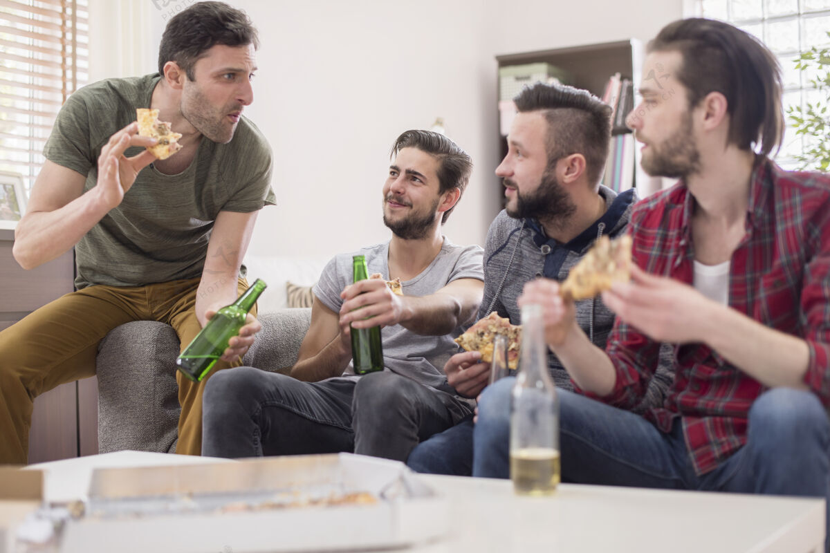 享受一群吃比萨饼喝啤酒的男人抱着笑聚会